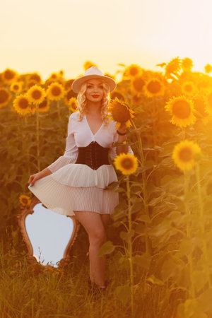 beautiful sweet sexy girl in a white dress walking on a field of sunflowers , smiling a beautiful smile,cheerful girl,style, lifestyle , ideal for advertising and photo sun shines bright and juicyの写真素材