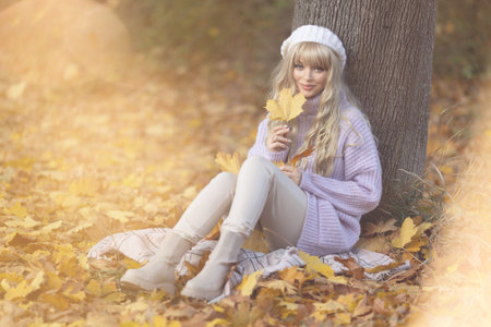 autumn leaves falling on happy young woman in forest. autumn landscapeの写真素材