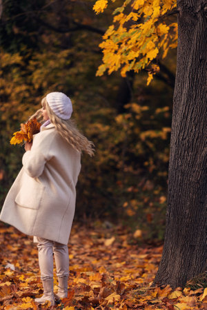 autumn leaves falling on happy young woman in forest. autumn landscapeの写真素材