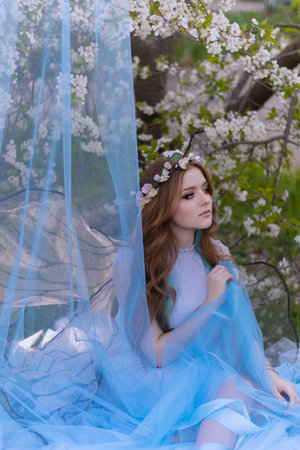 Art photo fantasy pixie butterfly. young fairy with glow wings holds bouquet flower. cute face, makeup red lipsの写真素材
