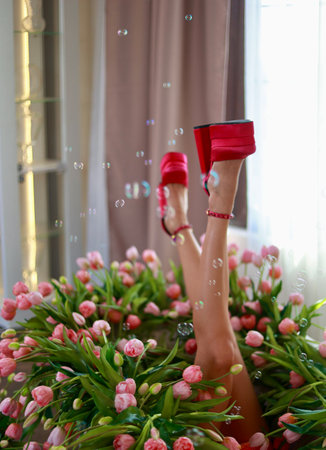 a bathroom full of pink tulips. Feet in pink glamorous shoes are visible from the bathroomの写真素材