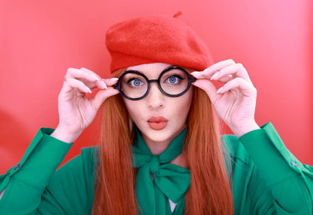 Portrait of beautiful cheerful redhead girl with flying curly hair smiling laughing looking at camera over red background.の写真素材