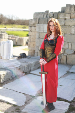 Warrior woman in golden armor with a sword on the seashore