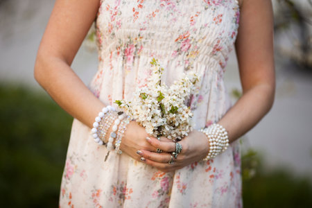 girl holds a branch of blossoming apricots in her hands. Close up of beautiful female hands holding a branch of blossoming fruit tree. delicate spring background. female hands on blurry background.の写真素材