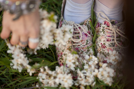 Feet of female relaxing at public park with pink flowers fall on green grass, nearly the end of...