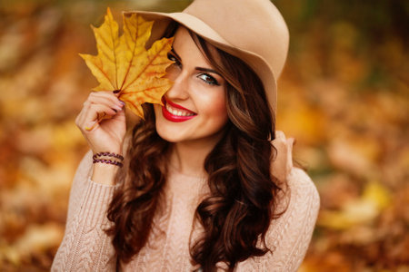Beautiful girl in red hat in autumn garden. autumn moodの写真素材