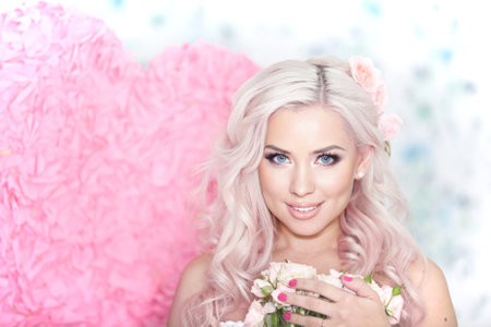 Young blonde woman with a bouquet of flowers on a pink background.spring moodの写真素材