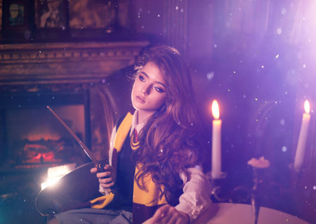 girl witch in glasses holds magic wand and magic book Cosplay. Halloween party, costume, holiday