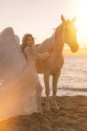 Young long hair woman in white shirt riding white horse on seascape backgroundの写真素材