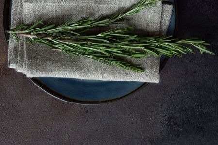 Table setting with modern plates decorated with fresh rosemary on stone backgroundの写真素材