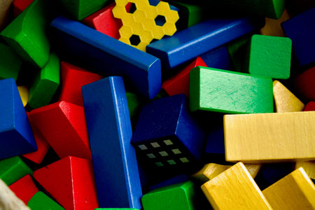 A top-down shot of various multi-colored wooden building blocks. Red, blue, green, and yellow toy...