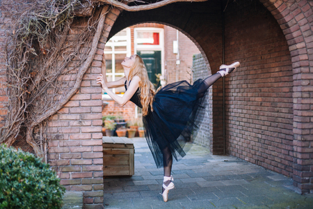 Young ballerina in ballet costume dancing and pointe shoes is in a beautiful pose dancing on the street.の写真素材