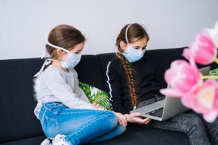 Online education, distance learning, home schooler. Childeren in medical mask studying homework during online lesson at home in digital tablet of laptop. Social distance on quarantine. Self-isolationの写真素材
