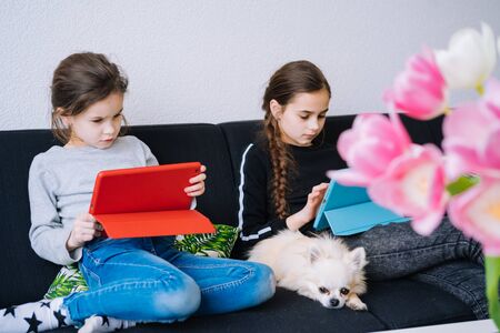 Online education, distance learning, home schooler. Childeren in medical mask studying homework during online lesson at home in digital tablet of laptop. Social distance on quarantine. Self-isolationの写真素材