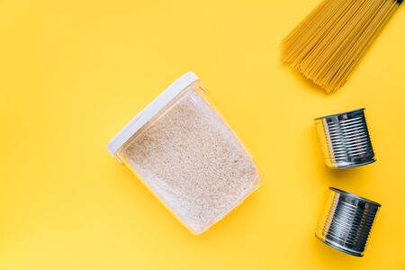 Food supplies crisis food stock for coronavirus quarantine isolation period in yellow background. different food in aluminum cans, Rice, pasta. Food delivery, Donation. top view. Copy spaceの写真素材