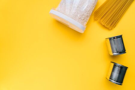 Food supplies crisis food stock for coronavirus quarantine isolation period in yellow background. different food in aluminum cans, Rice, pasta. Food delivery, Donation. top view. Copy spaceの写真素材