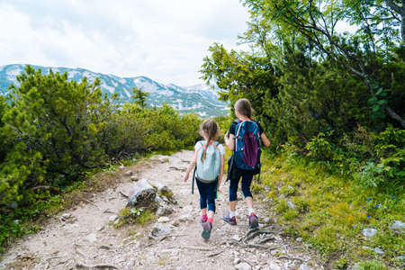 Children hiking on beautiful summer day in alps mountains Austria, resting on rock and admire amazing view to mountain peaks. Active family vacation leisure with kids.Outdoor fun and healthy activity.の写真素材