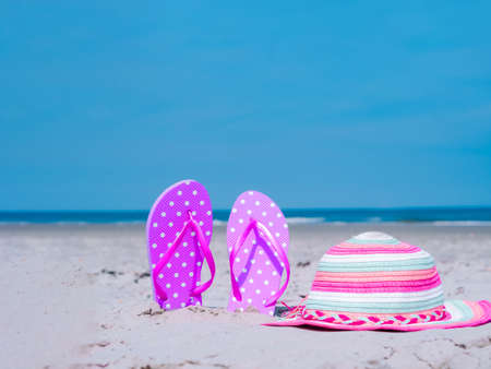 Sunlight Summer composition. Beach flip flops on tropical ocean sand. against blue sea and sky background. Beach Accessories Summer vacation concept of beach holiday, sea tour, warm sunny summerの写真素材