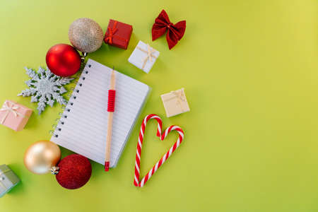 Christmas wishlist greeting card. Christmas composition. Present box, firtree branches, Xmas candies, red festive decorations on green background. Copy space. Christmas and new year holiday concept.の写真素材