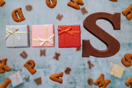 Dutch holiday Sinterklaas greeting Card. Gift boxes and traditional Saint Nicolas sweets falling or flying in motion or levitation. Pepernoten, chocolate letters. Concept children party five decemberの写真素材