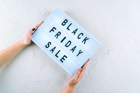 Top view of hands, black friday promotion sale words on lightbox, gift boxes, laptop, shopping cart and bag, credit bank card on table. Online shopping, Sale, e-shopping, ordering, payment.conceptの写真素材