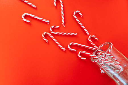 Christmas background. Composition with gift present box, fir tree branches and many Xmas striped candies, red festive decorations on red background. Copy space. Christmas and new year holiday conceptの写真素材