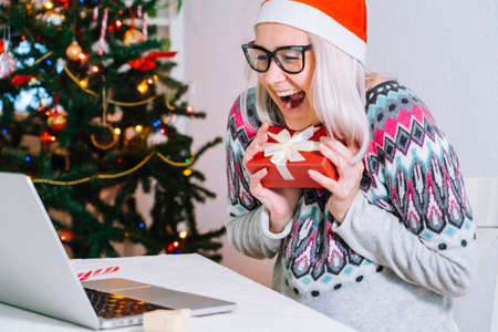 Christmas online family congratulations. Smiling girl at home using laptop computer notebook for...