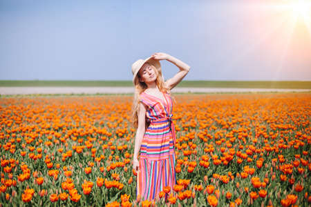 Beautiful red hair woman wearing in striped dress standing on colorful tulip flower fields in Amsterdam region, Holland. Magical Netherlands landscape with tulip field. Trevel and spring conceptの写真素材