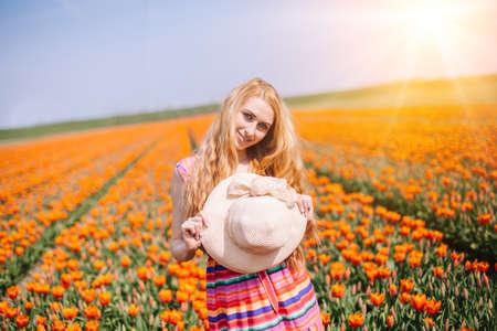 Beautiful red hair woman wearing in striped dress standing on colorful tulip flower fields in Amsterdam region, Holland. Magical Netherlands landscape with tulip field. Trevel and spring conceptの写真素材