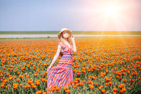 Beautiful red hair woman wearing in striped dress standing on colorful tulip flower fields in Amsterdam region, Holland. Magical Netherlands landscape with tulip field. Trevel and spring conceptの写真素材