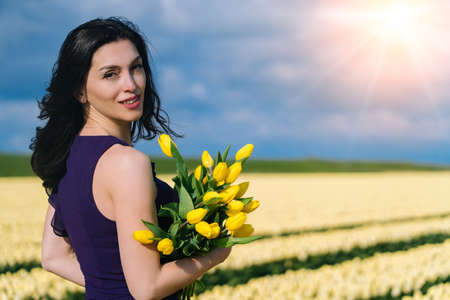 Beautiful Woman in summer dres standing in colorful tulip flower fields in Amsterdam region, Holland, Netherlands. Magical Netherlands landscape with tulip field in Holland Trevel and spring conceptの写真素材