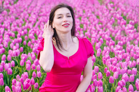 Beautiful Woman in summer dres standing in colorful tulip flower fields in Amsterdam region, Holland, Netherlands. Magical Netherlands landscape with tulip field in Holland Trevel and spring conceptの写真素材