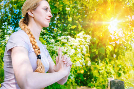 young woman doing yoga asana in park. girl stretching exercise in yoga position. happy and healthy woman sitting in lotus position and practicing yoga. meditation and sport on sunset outdoors.の写真素材