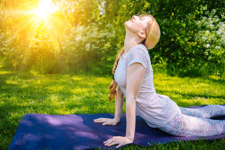 young woman doing yoga asana in park. girl stretching exercise in yoga position. happy and healthy...