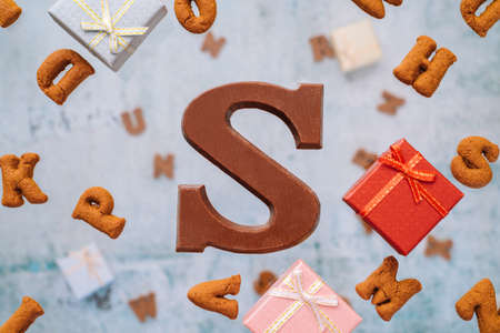 Dutch holiday Sinterklaas greeting Card. Gift boxes and traditional Saint Nicolas sweets falling or flying in motion or levitation. Pepernoten, chocolate letters. Concept children party five decemberの写真素材