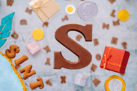 Dutch holiday Sinterklaas greeting Card. Gift boxes and traditional Saint Nicolas sweets falling or flying in motion or levitation. Pepernoten, chocolate letters. Concept children party five decemberの写真素材