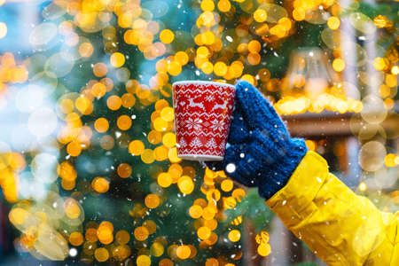 Girl walking in Christmas traditional market decorated with holiday lights in the evening. Winter portrait beautiful young woman outdoors in front of Xmas holidays decorations.の写真素材