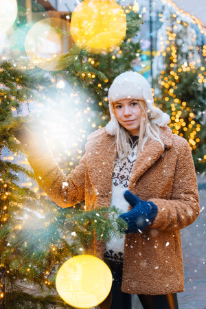 Girl walking in Christmas traditional market decorated with holiday lights in the evening. Winter portrait beautiful young woman outdoors in front of Xmas holidays decorations.の写真素材