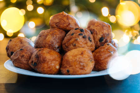 Oliebollen, traditional Dutch pastry for New Years Eve with sparkles. oil dumpling or fritter with sugar powder on top. Christmas tree lights bokeh on background. Typical food.の写真素材