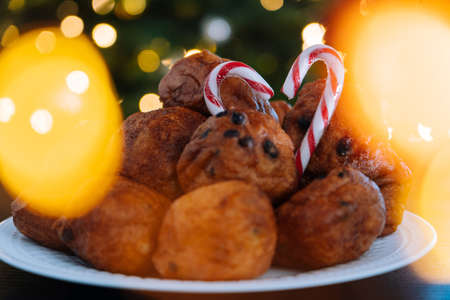 Oliebollen, traditional Dutch pastry for New Years Eve with sparkles. oil dumpling or fritter with sugar powder on top. Christmas tree lights bokeh on background. Typical food.の写真素材