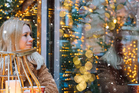 Girl walking in Christmas traditional market decorated with holiday lights in the evening. Winter portrait beautiful young woman outdoors in front of Xmas holidays decorations.の写真素材