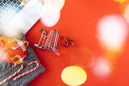 Christmas online shopping on laptop with credit card. New year decorations candy canes, shopping cart and presents box top view flat lay on red background. Merry Xmas winter holidays sales conceptの写真素材