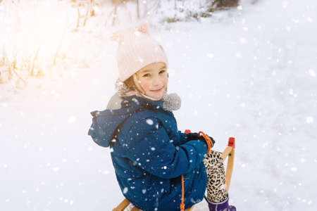 Two children ride on wooden retro sled on sunny winter day. Active winter outdoors games. Winter activities for kids. Children playing with snow in park.の写真素材