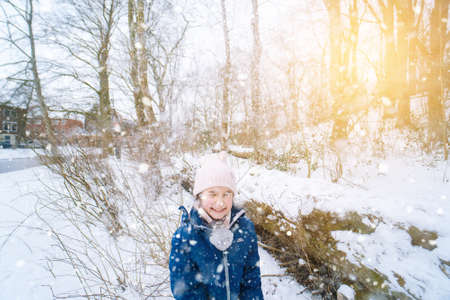 Children playing on snow in winter time. Happy laughing children in beautiful snowy winter forest on Christmas day. Happy childhood, active winter holidays concept.の写真素材