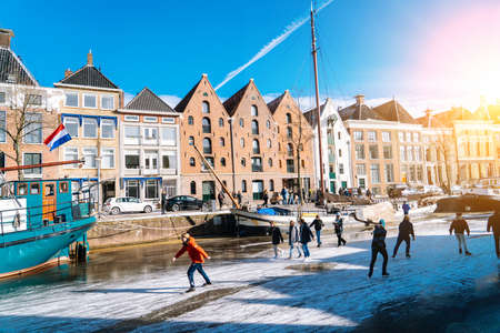 People ice scating on frozen canal in city center in Netherlands. Peoples making pictures, walking and skating on frozen canal in winter. Winter fun in cityGroningen. Netherlands. 14.02.2021.のeditorial素材