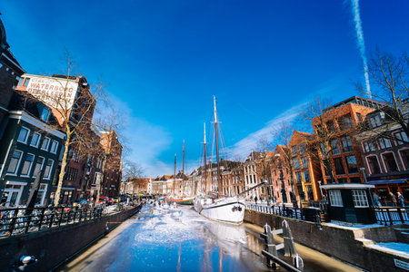 People ice skating on frozen canal in city center in Netherlands. Peoples making pictures, walking and skating on frozen canal in winter. Winter fun in cityGroningen. Netherlands. 14.02.2021.のeditorial素材