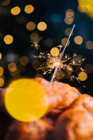Oliebollen, traditional Dutch pastry for New Years Eve with sparkles. oil dumpling or fritter with sugar powder on top. Christmas tree lights bokeh on background. Typical food.の写真素材