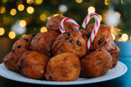 Oliebollen, traditional Dutch pastry for New Years Eve with sparkles. oil dumpling or fritter with sugar powder on top. Christmas tree lights bokeh on background. Typical food.の写真素材