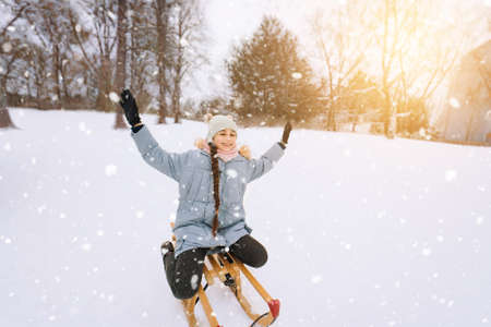 Two children ride on wooden retro sled on sunny winter day. Active winter outdoors games. Winter activities for kids. Children playing with snow in park.の写真素材