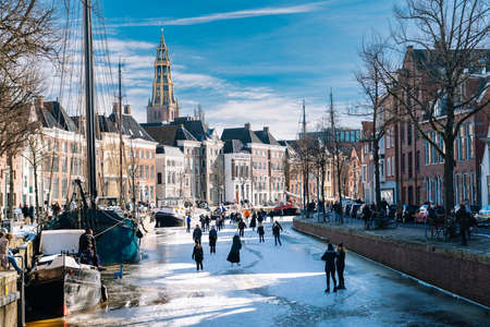 People ice skating on frozen canal in city center in Netherlands. Peoples making pictures, walking and skating on frozen canal in winter. Winter fun in cityGroningen. Netherlands. 14.02.2021.のeditorial素材